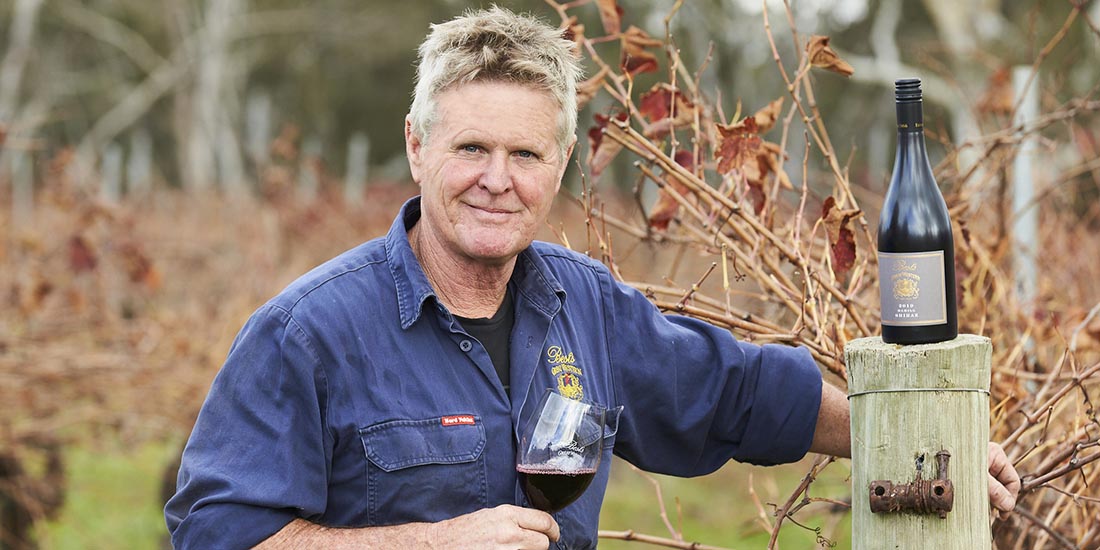 Man in vineyward with wine glass and bottle. 